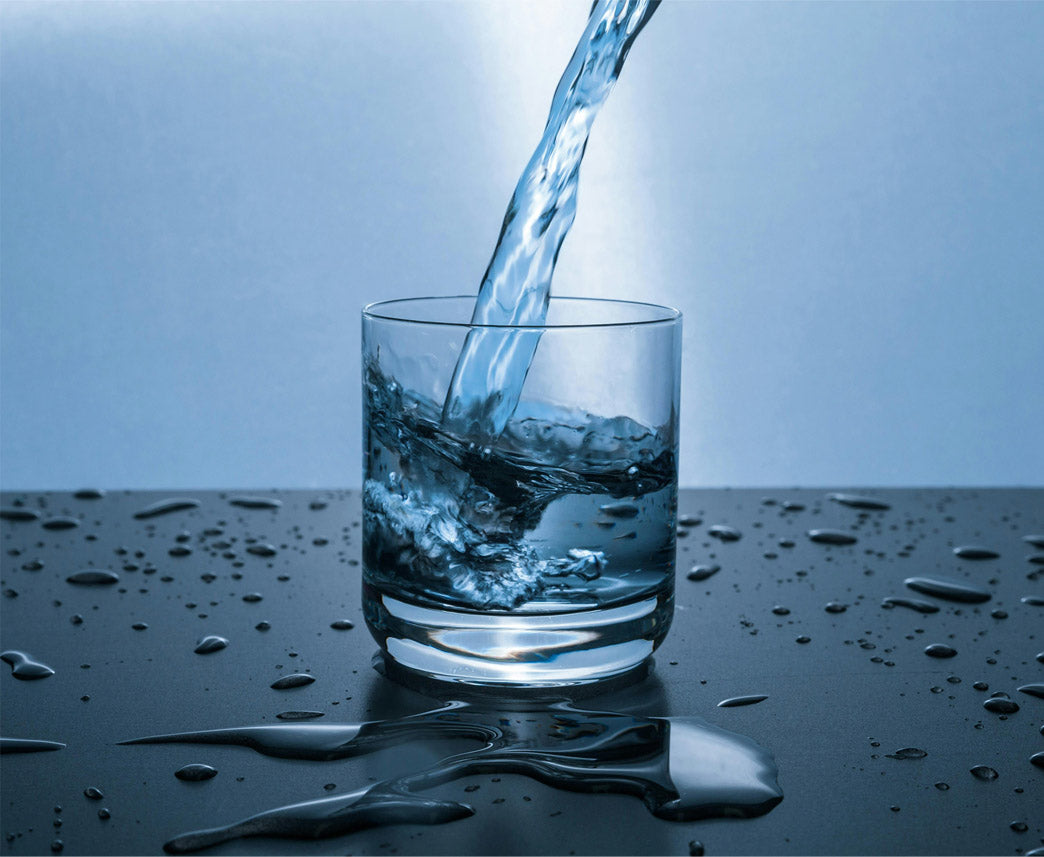 Vatten som fylls i ett glas, vattenstänk runt om
